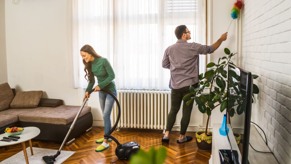 Young couple cleaning living room after moving in