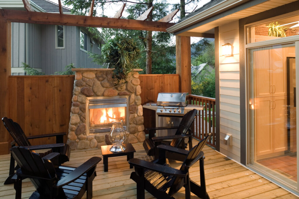 Outdoor patio with fireplace, muskoka chairs and barbeque grill
