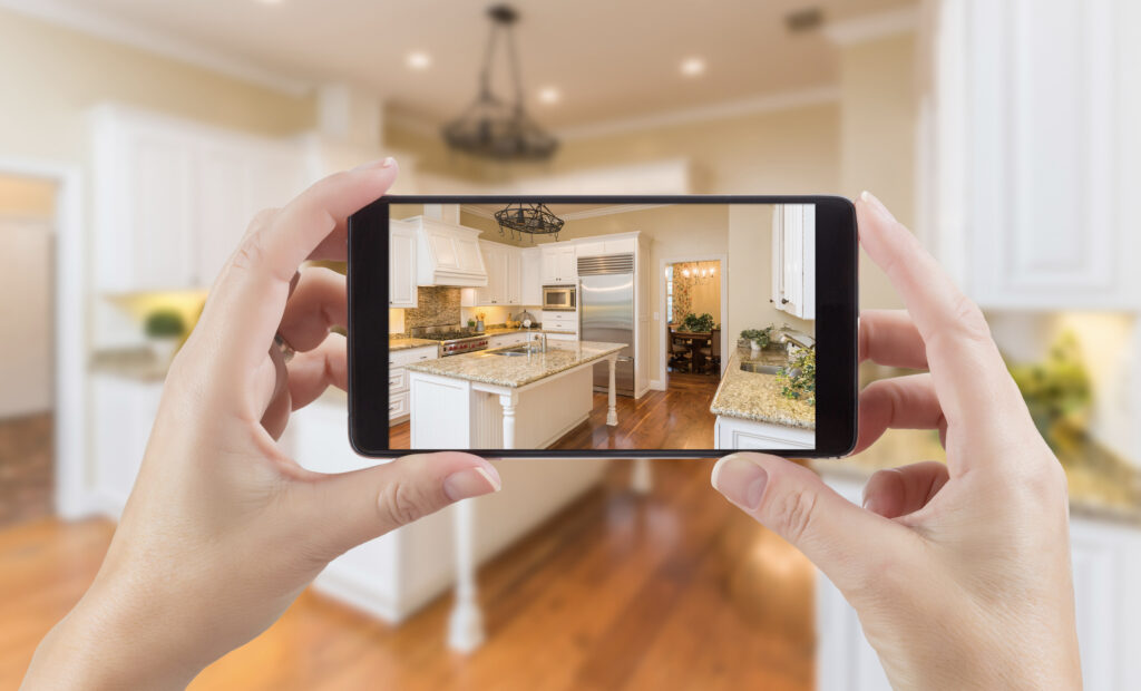 Hands taking a photo of renovated kitchen on a cell phone