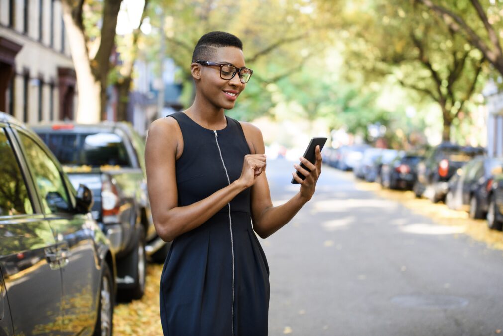 Young woman in the city using her cell phone to search for a property