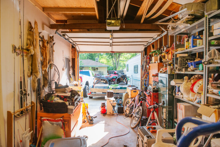 Garage lined with shelves full of things stored at home including tools, cleaning supplies, holiday decorations and sporting equipment.