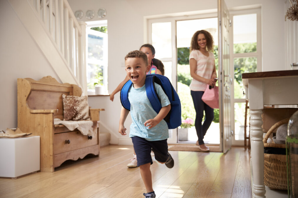 Young boy and his older sister excitedly running through the door after school