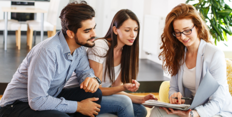 Young couple sitting on the couch, reviewing their finances with an advisor