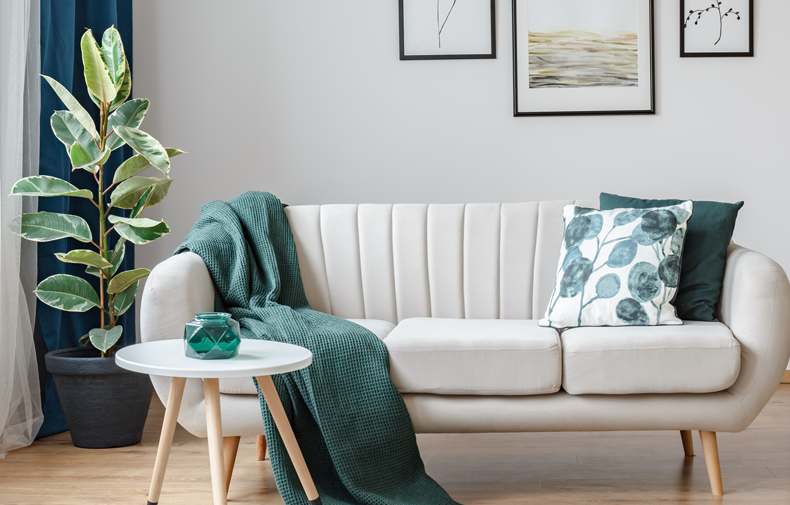 Modern living room with ivory couch and teal accent pillows and blanket