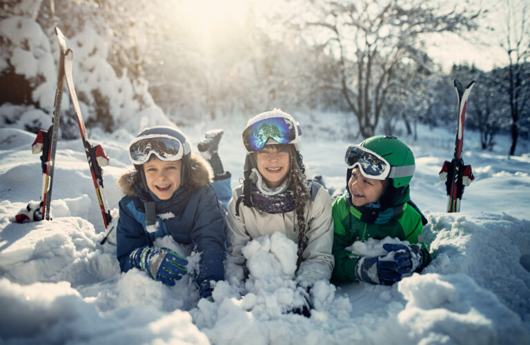 Three young skiers laughing, playing in the snow