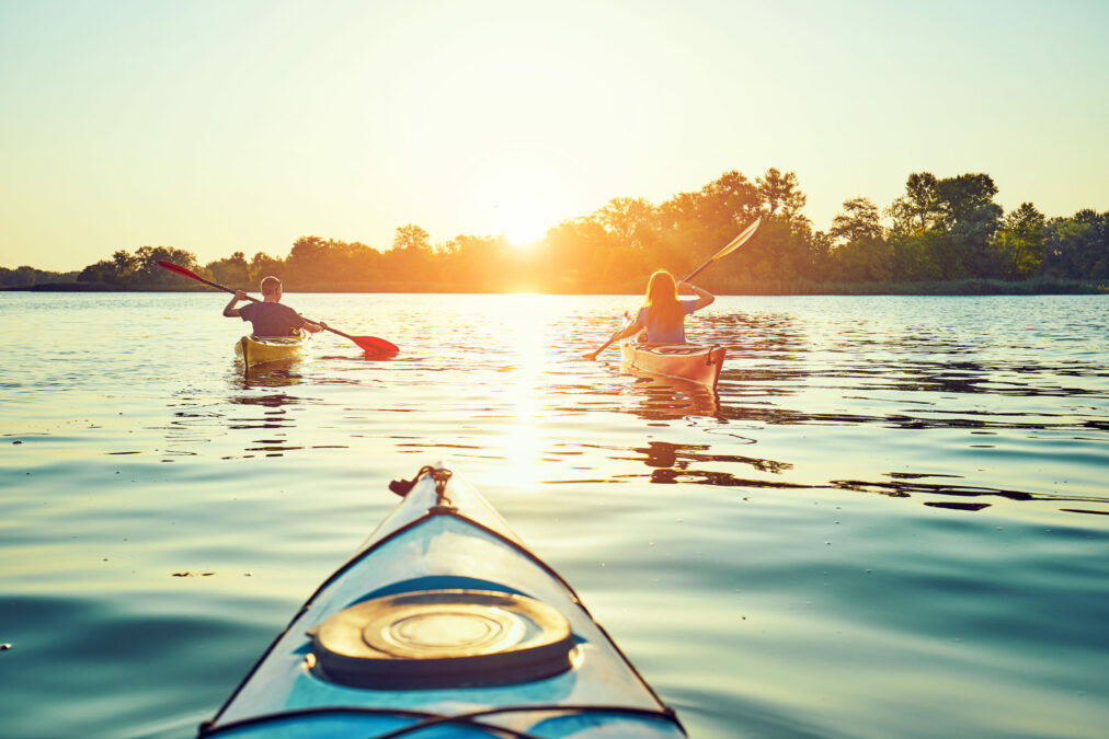 Two kayakers on a peaceful lake at sunset