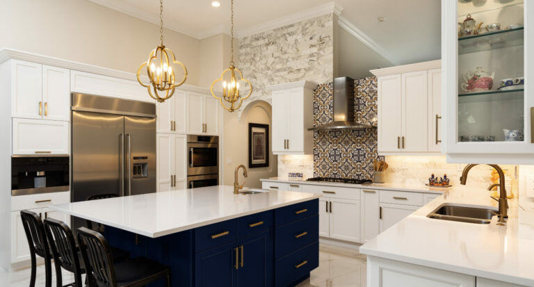Bright, modern, renovated white kitchen with blue island and gold fixtures