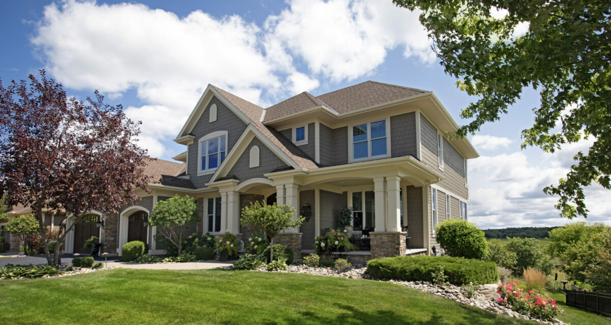 Exterior of luxury suburban home with beautiful landscaping on a sunny day