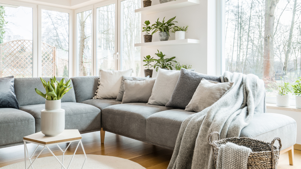 A grey L-shaped sofa in a bright living room overlooking the winter outdoors