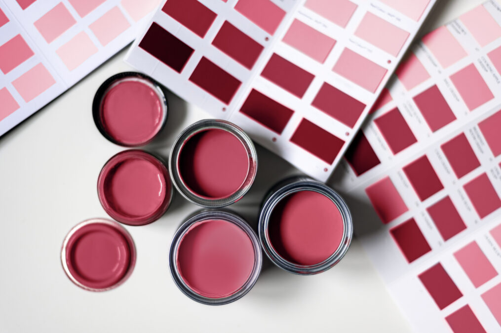 Small sample paint cans and swatches of a magenta-coloured paint