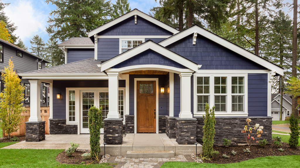A single-family Craftsman home with blue shingles surrounded by trees