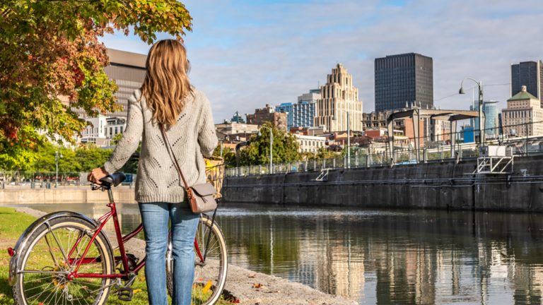 Portuguese woman riding her bike in the Old Port of Montreal and looking at the downtown area during a sunrise