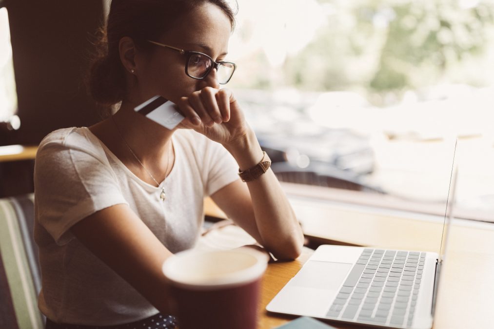 Woman in a cafe with her laptop having problems with her credit card