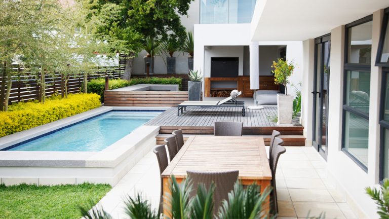 A modern backyard with an inground pool and patio with furniture
