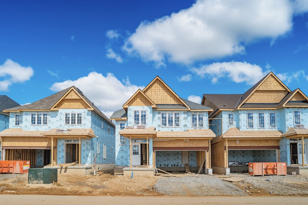 Three houses under construction in a new residential district on a sunny day