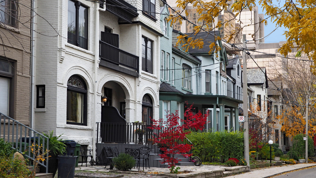 A street of historic semi-detached townhomes during the daytime in the fall