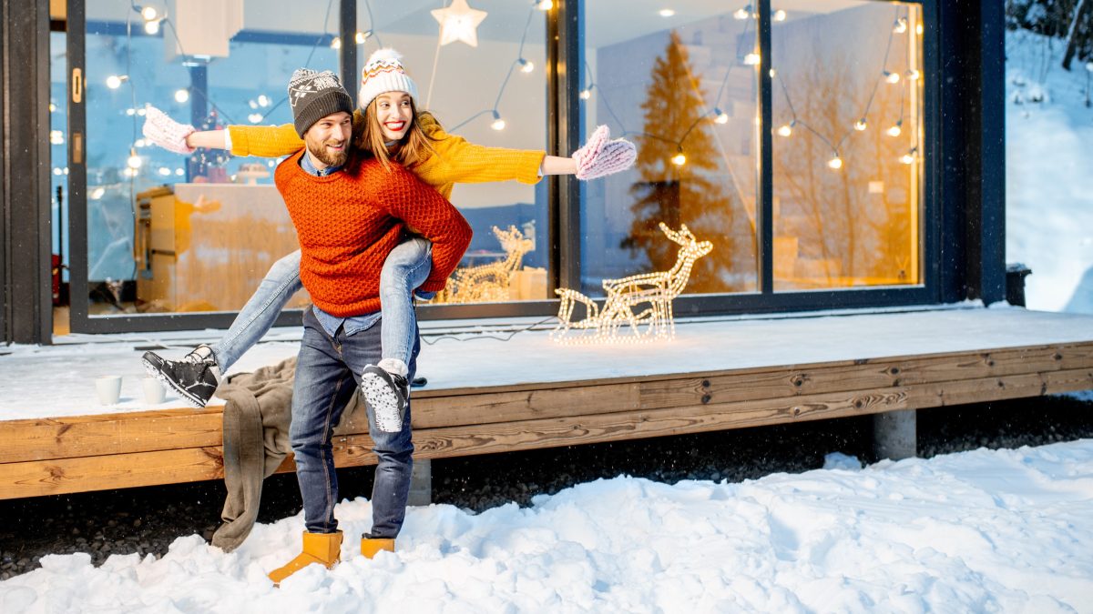 A man and woman in colourful sweaters play in the snow
