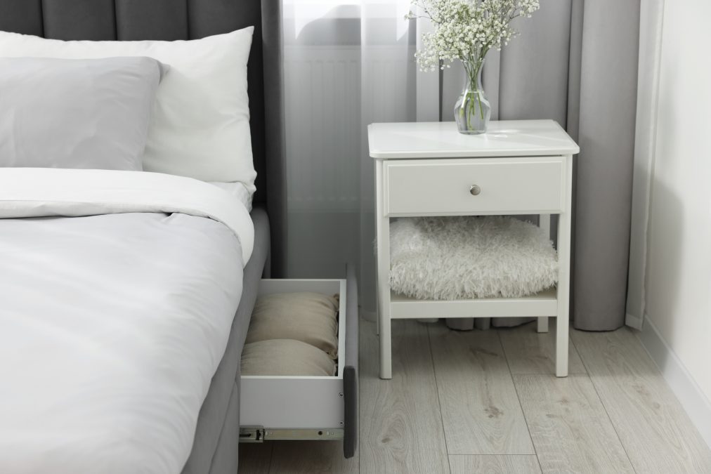 Storage drawer with bedding under comfortable bed in room