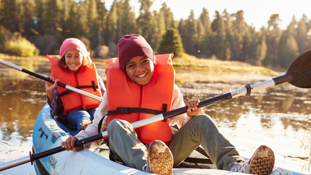 Two Children Rowing Kayak On Lake