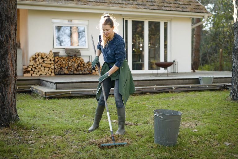 Woman working in the garden raking lawn