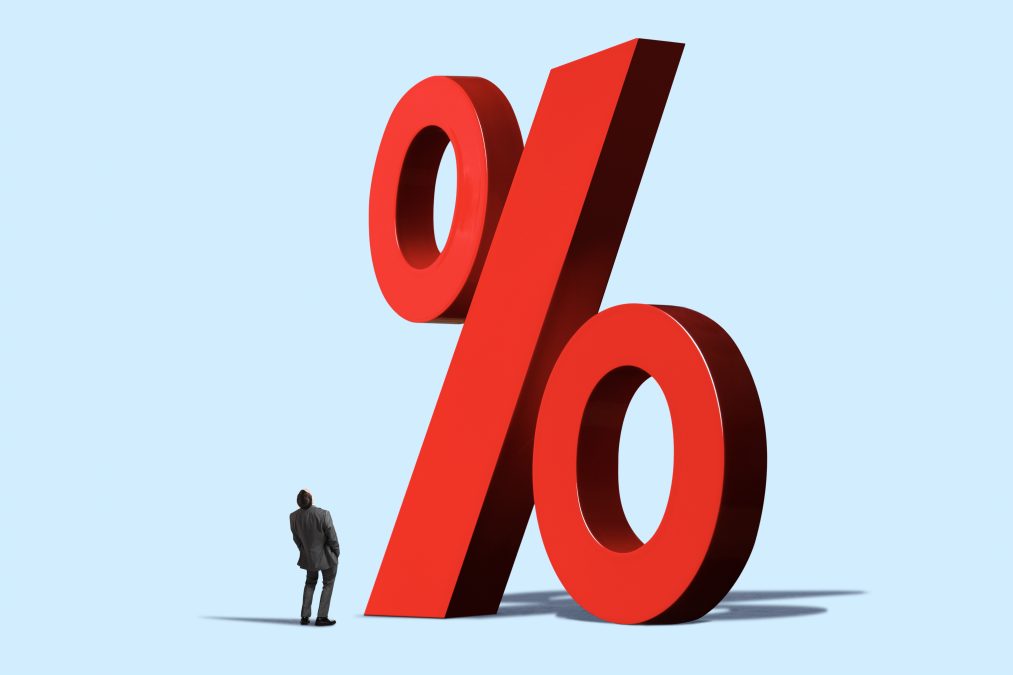 A man looks up at a large red percentage sign