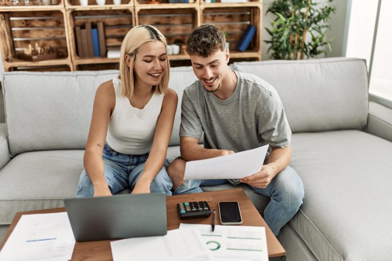 Young couple smiling happy using laptop at home.