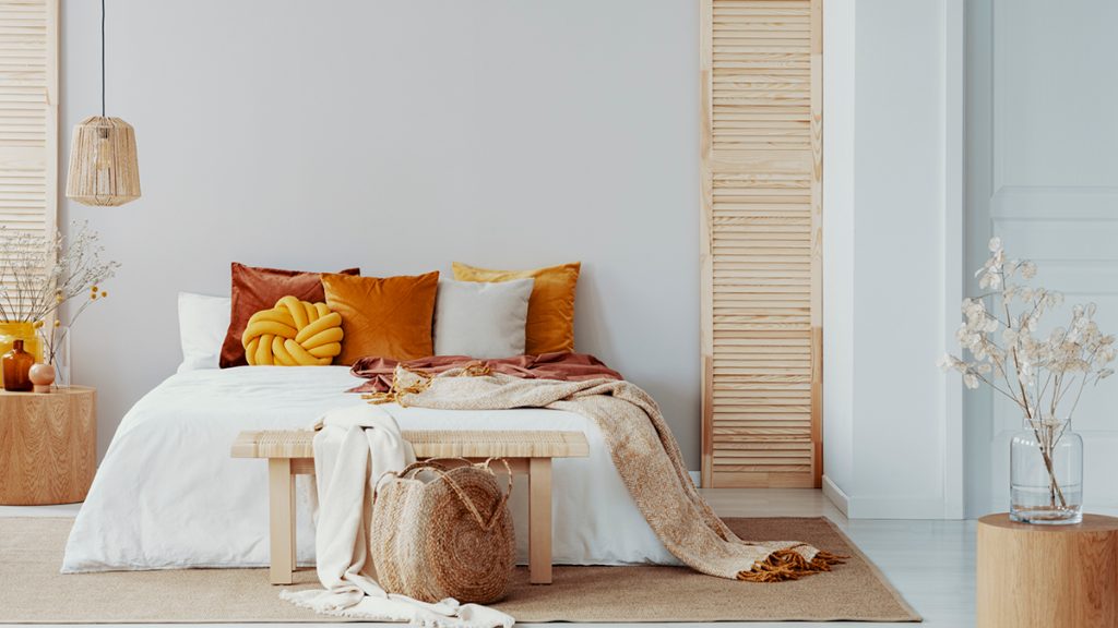 A double bed with orange pillows in a white bedroom