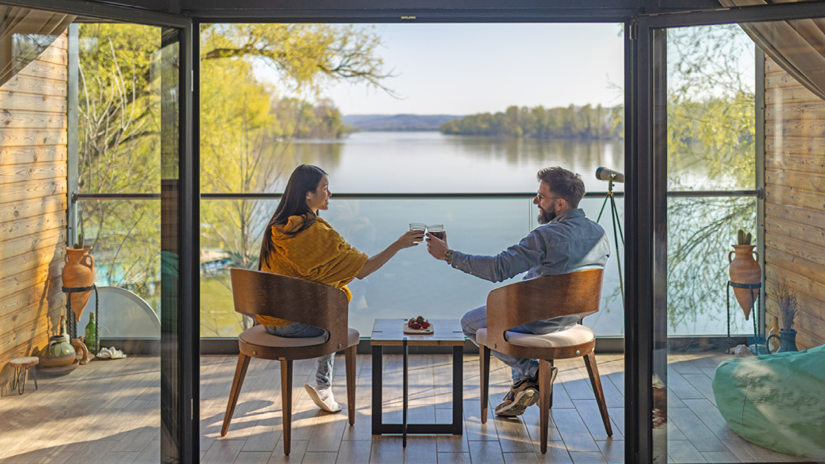 A couple sitting on a deck overlooking a lake during the day