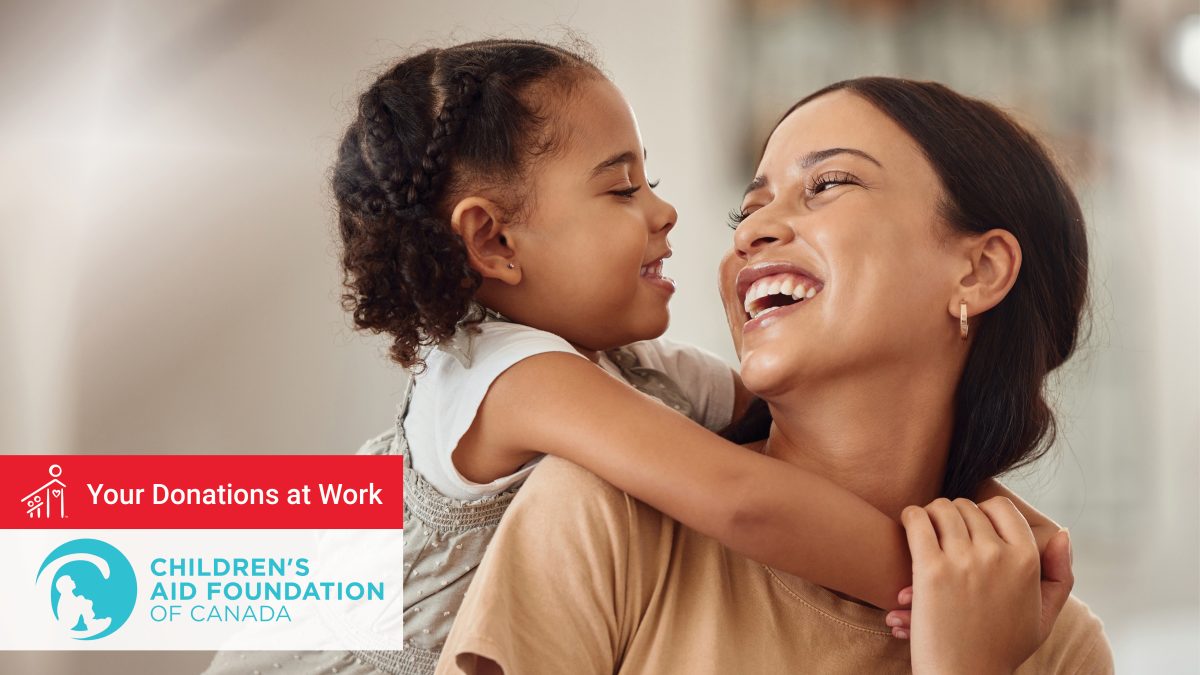A mother and young daughter embrace, smiling