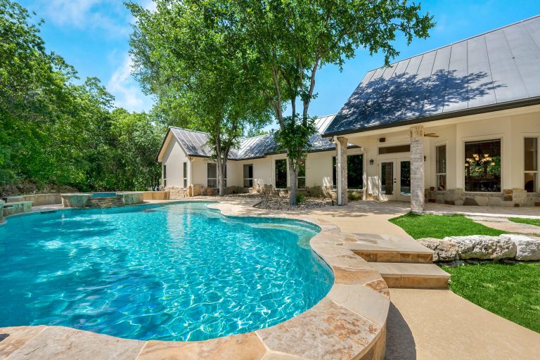 A clear inground pool outside a detached home on a sunny day