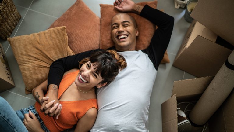 A young couple lying on the floor surrounded by moving boxes