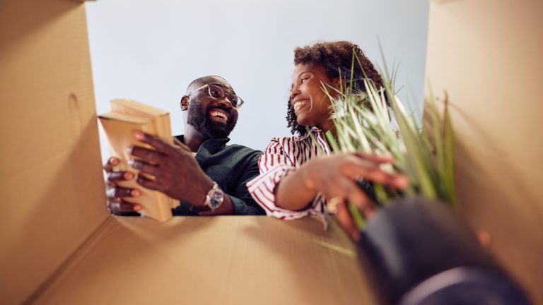 Low angle view of happy couple pulling items out of a moving box