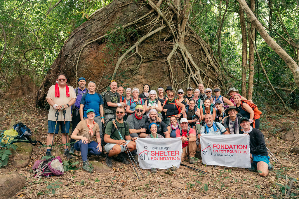 Hikers pose for a photo at the base of a large tree