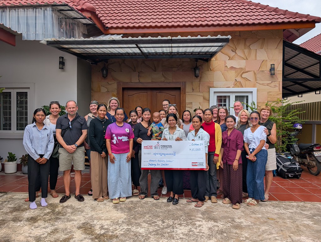 A group of people pose for a photo holding a large donation cheque