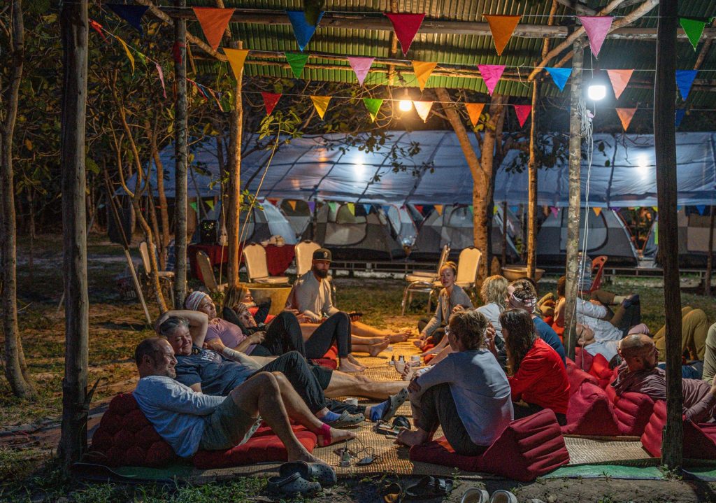 A group of hikers rest under a tent at night