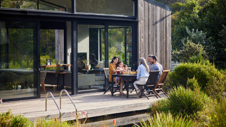 Multi-generation family having lunch while sitting around a dining table outside on their patio at home in summer
