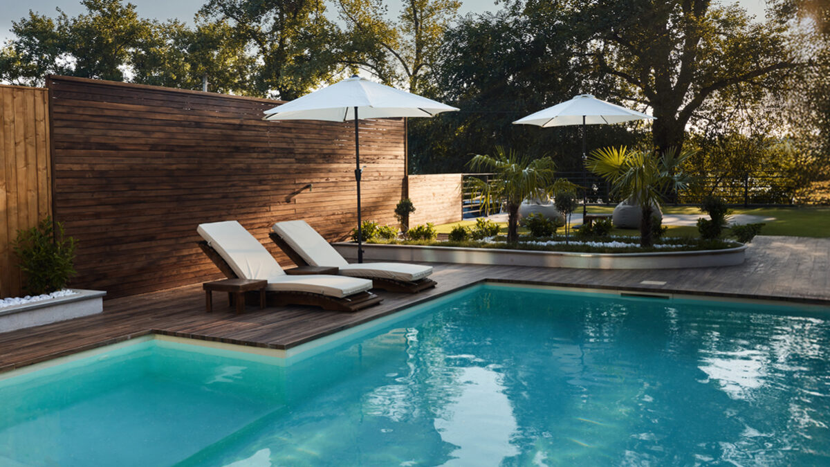 A shady backyard with a pool and white umbrellas