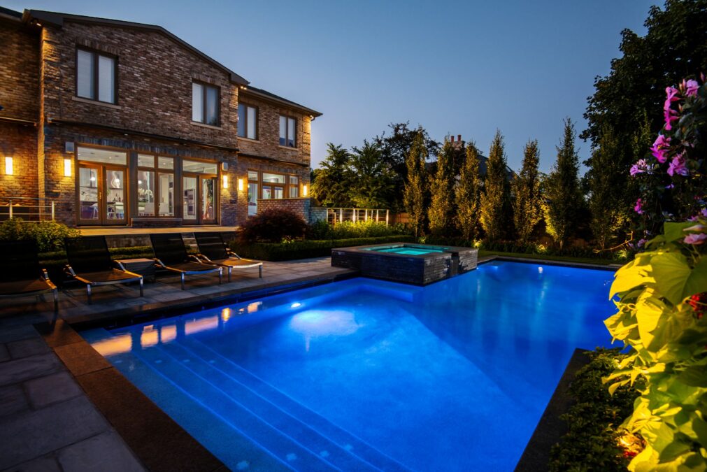 Back yard with large swimming pool and rear deck at night