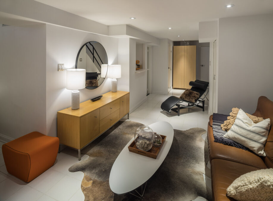 Bright, finished basement living space with warm lighting and comfortable furniture