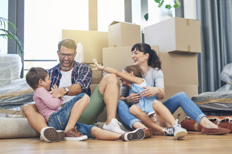 Family sitting on floor of home in front of moving boxes