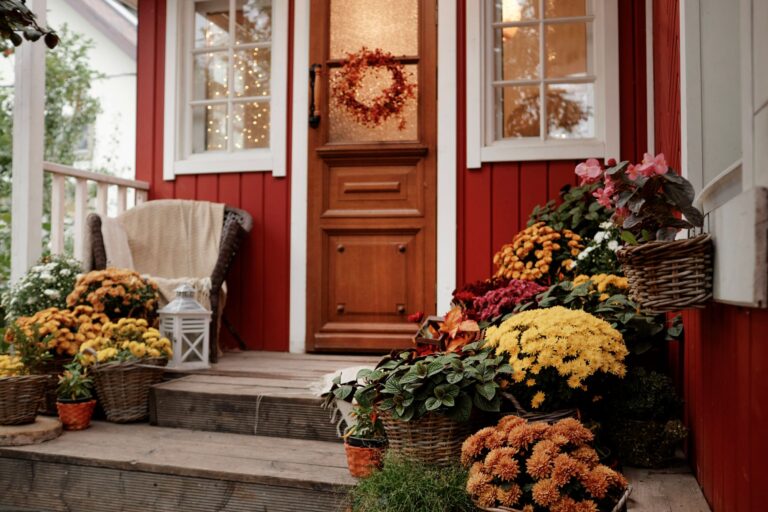 Red front door of a home with plants during the fall